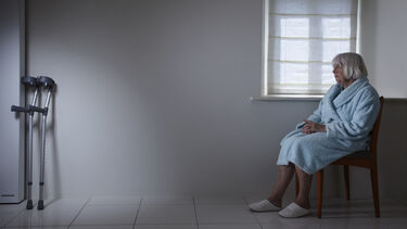 A picture of an elderly woman seated alone, out of reach of crutches