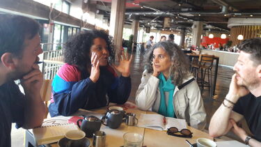 A photograph of four people in a meeting in a restaurant