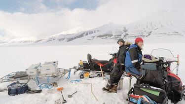 Two people sat with their kit on the snow
