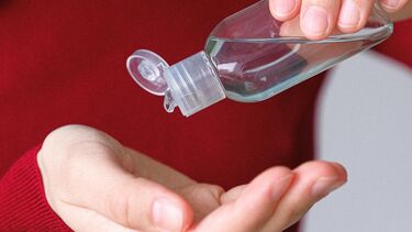 Close up image of a person's hands, pouring hand sanitiser from a bottle into their hand