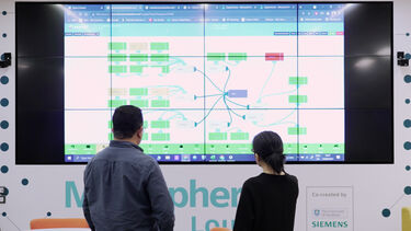 Energy Institute members stand in front of a screen showing the SCEnAT 4.0 software. 