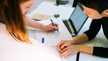 Woman discusses with colleague whilst annotating diagram