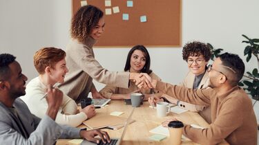 A photograph of several people around a table, working collaboratively.
