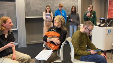 7 people during the rehearsal of a play. in the foreground 3 people sit as if on a tram