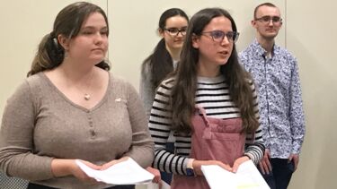 two students in front and two in the background reading a script and speaking