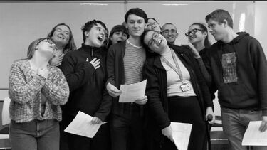 Black andWhite image of group of students who all admire the central figure