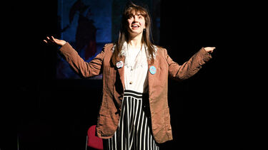 Student on stage with arms stretched out
