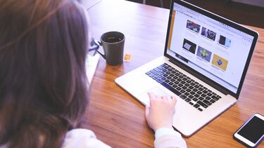 A person moving the trackpad on a laptop sitting at a desk