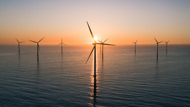 Wind turbines offshore as the sun sets