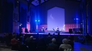 Audience watching two performers on stage in large hall