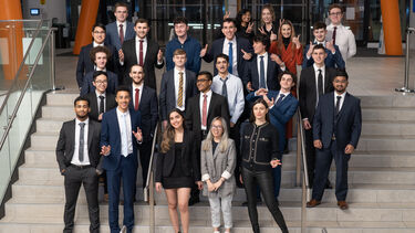 A group of students stood on steps in suits, who part of the Twikker Fund and USIS Society