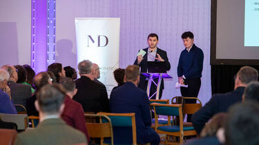 Economics students Will and Ralph speaking about the Twikker Fund on stage at an event