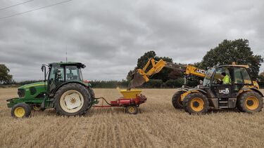 A tractor for spreading receiving crushed basalt from a front-loader at our field site in Harpenden