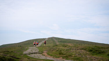 A photo showing three walkers climbing Mam Tor
