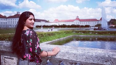 Student leaning on a stone railing with a german castle in the background