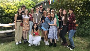 Group of about 16 students in a sunny garden 
