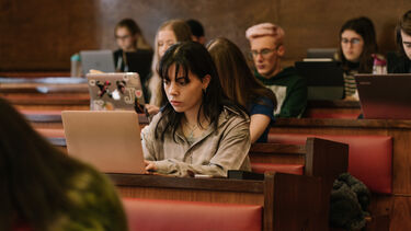 students sat in a lecture theatre using laptops