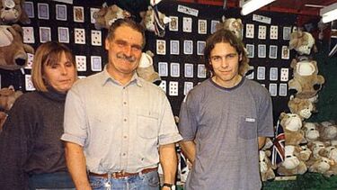 Two generations of the Smith fairground family. From left to right Judy, John and John Jnr.  Smith in front of their games stall c.1990s. Harry Russell Collection