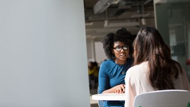 2 women sat opposite each other at a table.