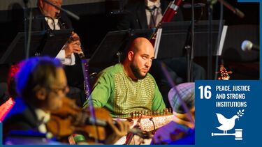 Musician playing traditional Afghan instrument on stage
