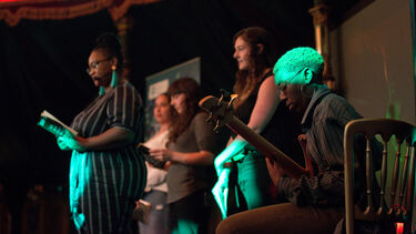 Festival of the Mind in the Spiegeltent, a multiple people read from a book as a person plays guitar