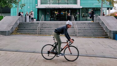 Man on bike cycling down leavygrave road cycle path past Information Commons building