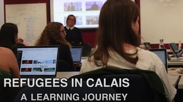 A scene in a classroom with a tutor in front of a screen and students viewed from the back