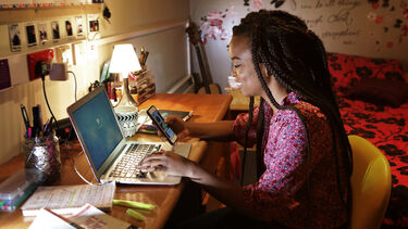 Student at home typing on laptop