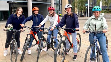5 students on bikes looking at the camera smiling
