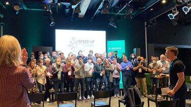 Group of employees stood at the front of a room giving round of applause