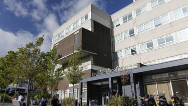 Exterior image of medical school, set against blue sky with trees infront
