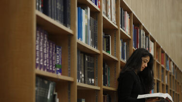 Image of a person reading a book in a library.