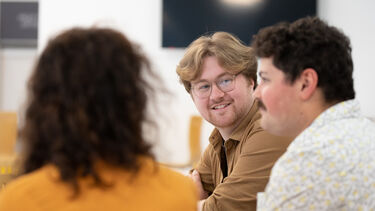 Three researchers chatting in a cafe and smiling