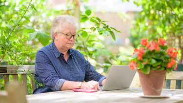 Woman over 50 working on laptop in garden