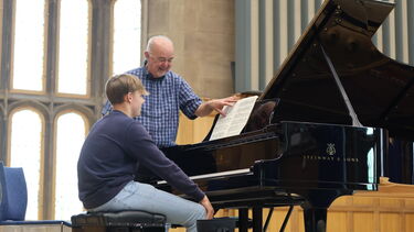 Piano lesson with teacher and student on stage with Steinway piano