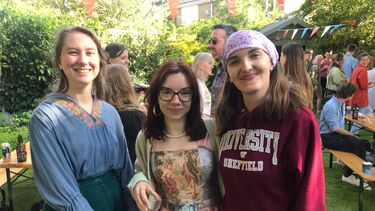 three young women smiling at the camera during an outdoor party