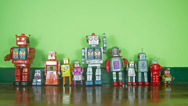 Photograph of toy robots lined up against a green background