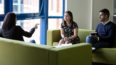 Three PhD students talking and smiling