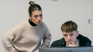 A man and a woman looking at a computer screen. 