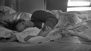 older woman laying in messy bed