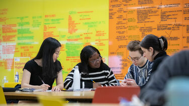 4 people studying at the Library table.