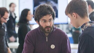 An individual explaining an exhibit to a younger individual. The exhibit appears to be focused around animal bones.