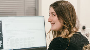 A girl sat in front of a PC screen.