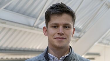 Tobias Darroch wearing a white shirt and a grey jumper.