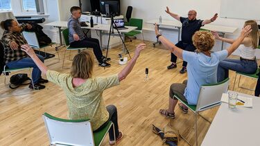 six people sat in a circle doing a breathing exercise