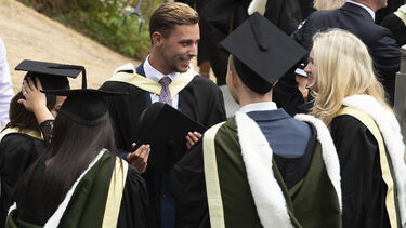 Group of graduates looking happy outside on concourse 