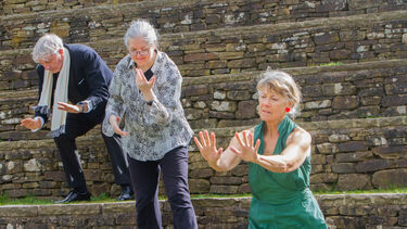 Two older women and a man posing as part of a dance routine
