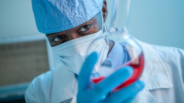 Masked researcher looking at the specimen in a glass bottle