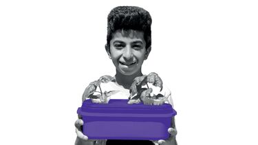 A refugee child is smiling as he holds a container growing crops.