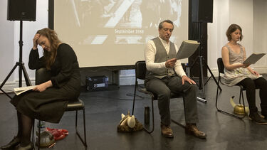 Three people sat on chairs with scripts in their hands